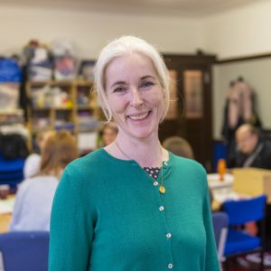 Catherine Coulthard. Smiling white woman with silver hair, blue eyes and a green cardigan.