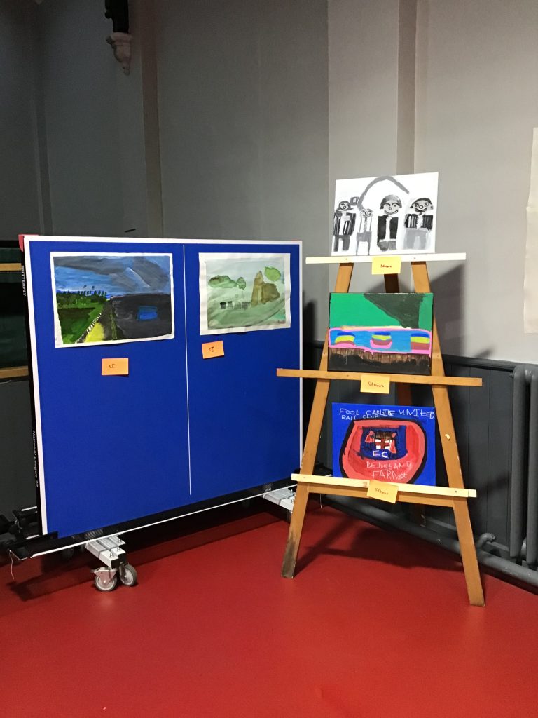 A display of artwork including painted portraits and landscape